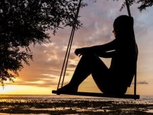 A woman ponders life while sitting on a swing. Mid-life crisis, quarter-life crisis, and tri-life crisis or tri-life crisis is a very real and challenging experience to overcome