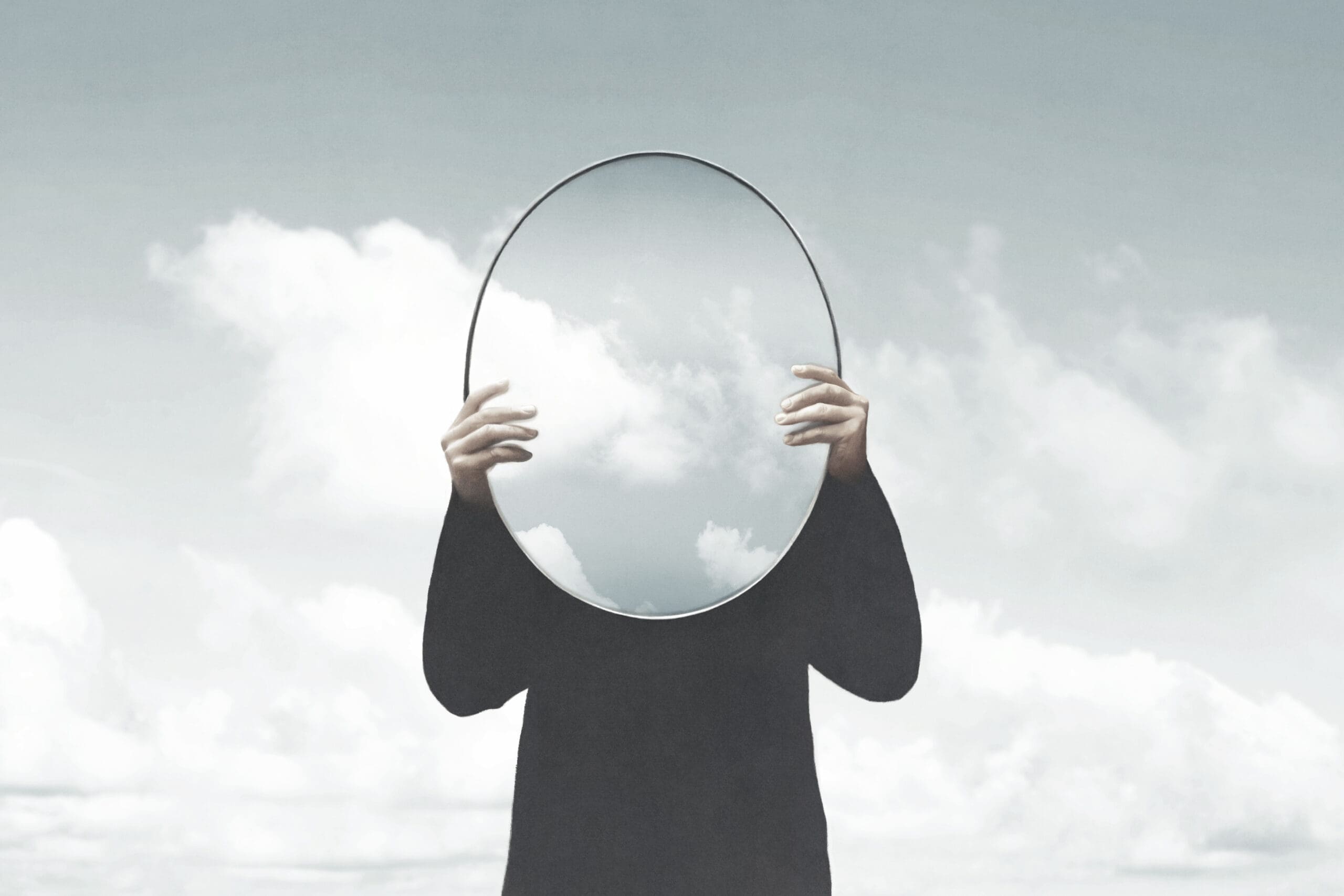 A human holds a mirror reflecting no face, no identity. Deconstruction is the best way to discover authentic you